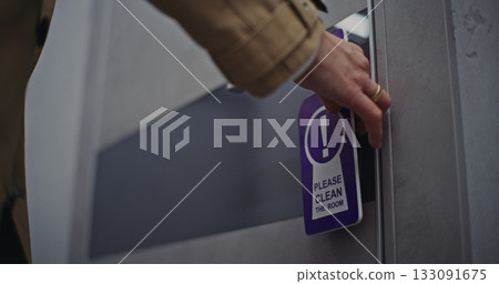 Female Hotel Guest Exits Room and Places Please Clean Room Sign on Door Handle Female Hotel Guest Exits Room and Places Please Clean Room Sign on Door Handle 133091675