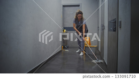 Hotel Housekeeper in Grey Uniform Mopping Hallway Floor 133091710
