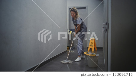 Hotel Housekeeper in Grey Uniform Mopping Hallway Floor Hotel Housekeeper in Grey Uniform Mopping Hallway Floor 133091715