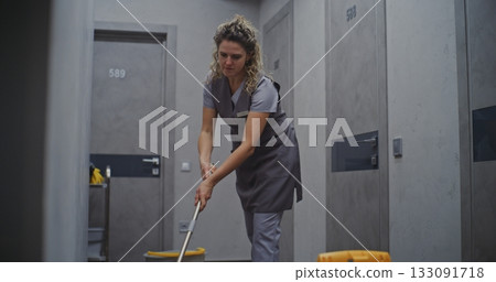 Hotel Housekeeping Staff Member Cleaning Hallway With Mop 133091718