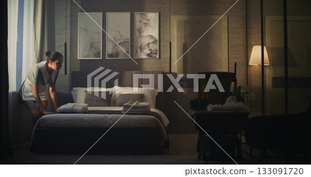 Female Hotel Employee Enters Dark Suite Refresh Room, Emphasizing Comfort and Attention to Guests 133091720