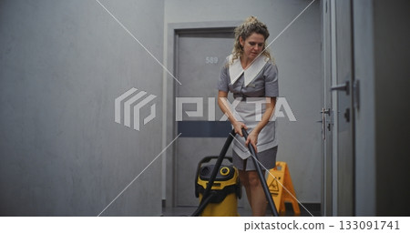 Female Cleaning Staff Vacuuming Floor in Hotel Corridor 133091741