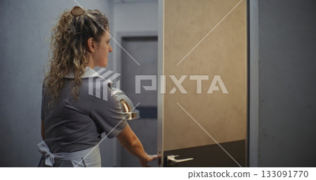 Friendly Female Hotel Attendant in Grey Uniform Delivering Room Service Friendly Female Hotel Attendant in Grey Uniform Delivering Room Service 133091770
