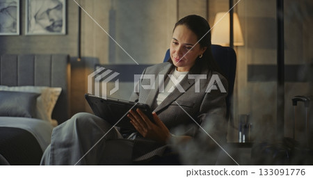Businesswoman in Cozy Hotel Room Reviews Presentations on Tablet Businesswoman in Cozy Hotel Room Reviews Presentations on Tablet 133091776