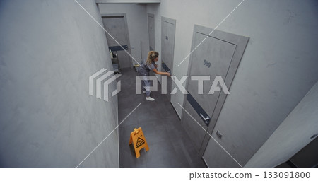 Hotel Cleaning Staff in Neat Uniform Thoroughly Cleans Door With Gentle Cloth and Disinfectant Hotel Cleaning Staff in Neat Uniform Thoroughly Cleans Door With Gentle Cloth and Disinfectant 133091800