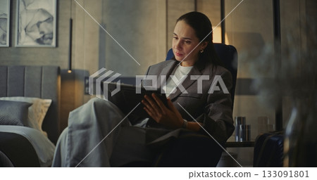 Elegant Woman Sits in Soft Armchair, Using Tablet For Video Calls and Work Communication Elegant Woman Sits in Soft Armchair, Using Tablet For Video Calls and Work Communication 133091801