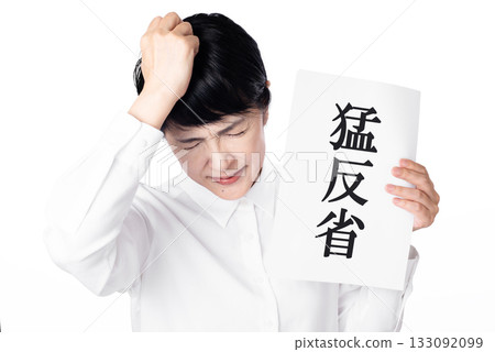 A senior woman wearing a white shirt holding a piece of paper that says "deep remorse" and holding her head 133092099