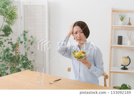 A woman with a troubled expression holding a salad A woman with a troubled expression holding a salad 133092189