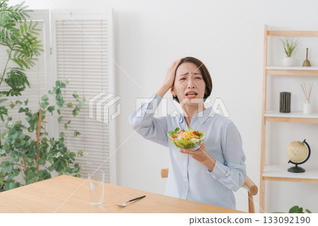 A woman with a troubled expression holding a salad A woman with a troubled expression holding a salad 133092190