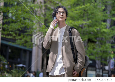 A man in his 30s talking on a smartphone in the city A man in his 30s talking on a smartphone in the city 133092502