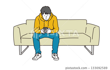 圖:一個男人坐在沙發上,看著手機消磨時間 圖:一個男人坐在沙發上,看著手機消磨時間 133092589