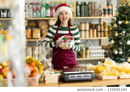 European girl seller stands in trading hall grocery, offer to buy candies at New Year Eve European girl seller stands in trading hall grocery, offer to buy candies at New Year Eve 133093184