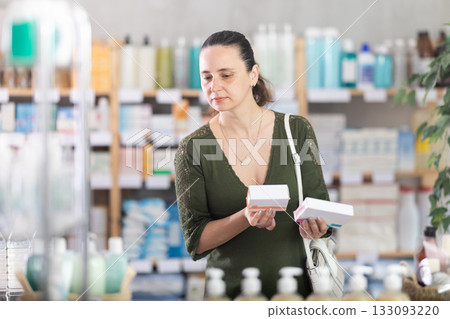 Middle-aged woman customer choosing pills in box in drugstore Middle-aged woman customer choosing pills in box in drugstore 133093220
