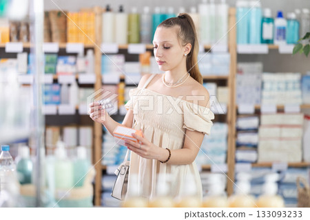 Woman in a summer dress chooses pills for toxicosis Woman in a summer dress chooses pills for toxicosis 133093233