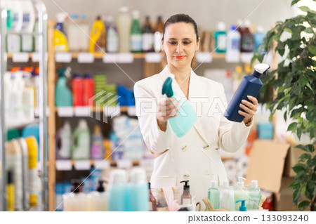 Adult woman chooses cleaning spray in store Adult woman chooses cleaning spray in store 133093240