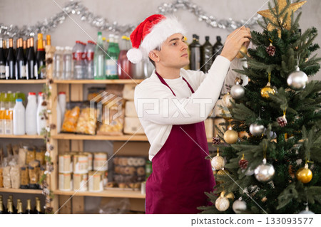 Young salesman decorates grocery store for christmas 133093577