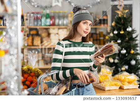 Wwoman with a basket of groceries buys dried jamon in supermarket Wwoman with a basket of groceries buys dried jamon in supermarket 133093657