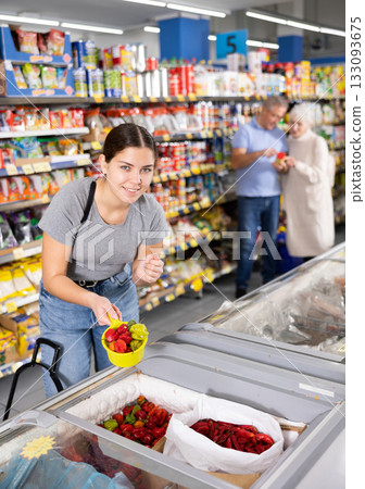 Young woman purchaser choosing frozen pepper in supermarket 133093675