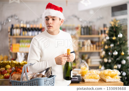 Young man examines alcohol wine bottle in store. 133093688
