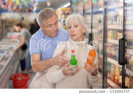 Man and woman purchasers choosing cool drink in supermarket 133093737