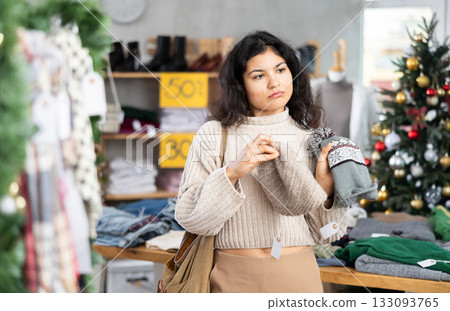 Latina chooses a hat against the background of a Christmas tree 133093765