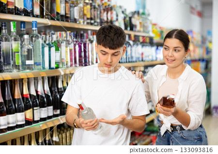 Man and woman choose high-quality alcoholic drink in supermarket 133093816