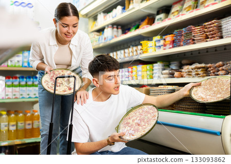 Young couple looking to buy frozen pizza in supermarket 133093862