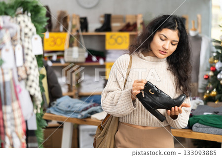 Latina chooses heeled boots on the background of a Christmas tree 133093885