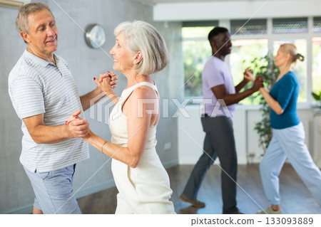 Mature male novice student of fitness studio practices paired Latin American rumba dance Mature male novice student of fitness studio practices paired Latin American rumba dance 133093889