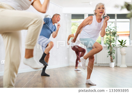 Group of mature sports women and man in activewear exercising dynamic dancing movemens in modern gym studio Group of mature sports women and man in activewear exercising dynamic dancing movemens in modern gym studio 133093895