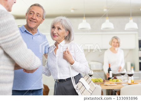 Two elderly couples meet for holiday dinner at home. Greet each other 133093896