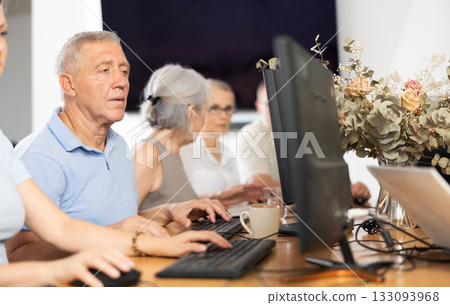 Concentrated elderly man immersed in using computer in library Concentrated elderly man immersed in using computer in library 133093968