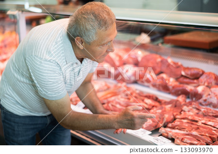 Adult man buyer chooses beef in butcher shop Adult man buyer chooses beef in butcher shop 133093970