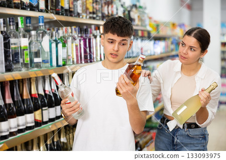 Young girl and guy choosing alcoholic drinks in store 133093975