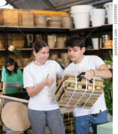 guy and girl choose folding wooden furniture for country house in store 133093998