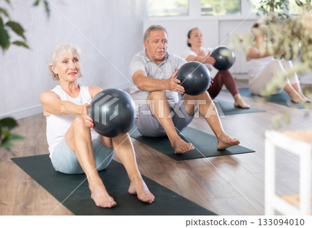 Elderly woman doing pilates with soft ball in studio Elderly woman doing pilates with soft ball in studio 133094010