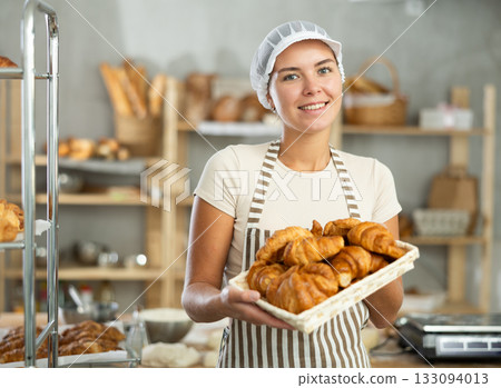 Young woman are standing in kitchen with basket of finished products croissant 133094013