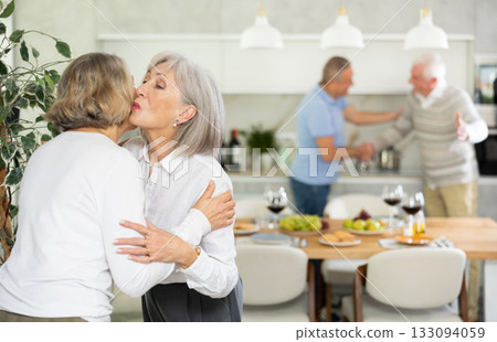 After chatting and gatherings, two mature women friends hug and kiss goodbye. 133094059