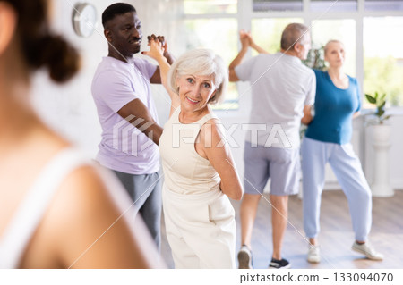 Mature men and women practicing Ballroom dances in training room Mature men and women practicing Ballroom dances in training room 133094070