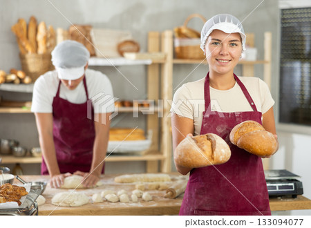Young female baker holding bread in square wicker basket 133094077