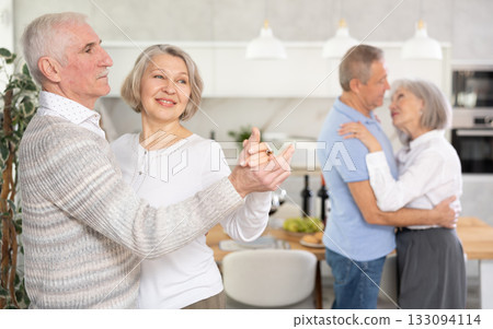 Senior men and women doing couple dancing during house party. Senior men and women doing couple dancing during house party. 133094114