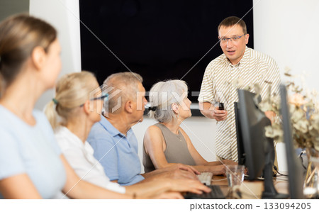 Male teacher teaching elderly people how to use computer Male teacher teaching elderly people how to use computer 133094205