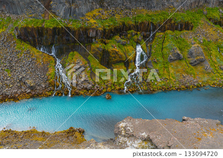 Turquoise water flows through Sigoldugljufur Canyon, Iceland, with moss covered cliffs and cascading waterfalls over basalt rock formations. Turquoise water flows through Sigoldugljufur Canyon, Iceland, with moss covered cliffs and cascading waterfalls over basalt rock formations. 133094720