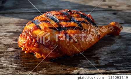 Deliciously grilled chicken leg quarter seasoned and presented on rustic wooden surface offering 133095349