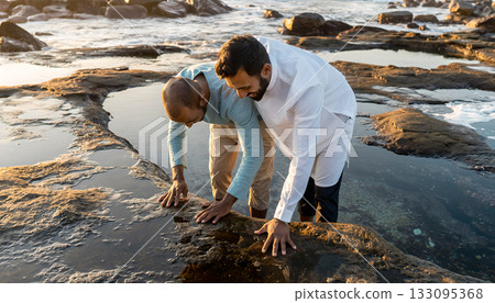 Two men explore the ocean shore discovering the nature while experiencing coastal environment 133095368