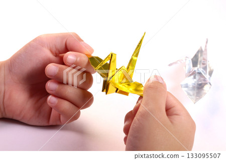 孩子的手拿著一隻折好的紙鶴。 孩子的手拿著一隻折好的紙鶴。 133095507
