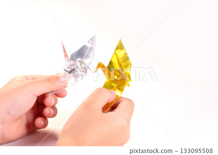 孩子的手拿著一隻折好的紙鶴。 孩子的手拿著一隻折好的紙鶴。 133095508