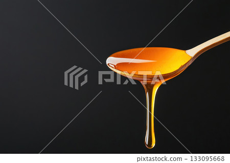 Elegant macro shot of organic honey dripping from a spoon, natural sweeteners, pure and wholesome food 133095668