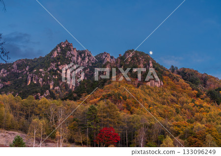 The moon rising over Mt. Mizugaki and autumn leaves in the evening from Mizugaki Natural Park in autumn The moon rising over Mt. Mizugaki and autumn leaves in the evening from Mizugaki Natural Park in autumn 133096249