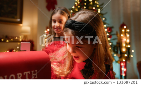 Little sisters putting letters into Santa mailbox 133097201